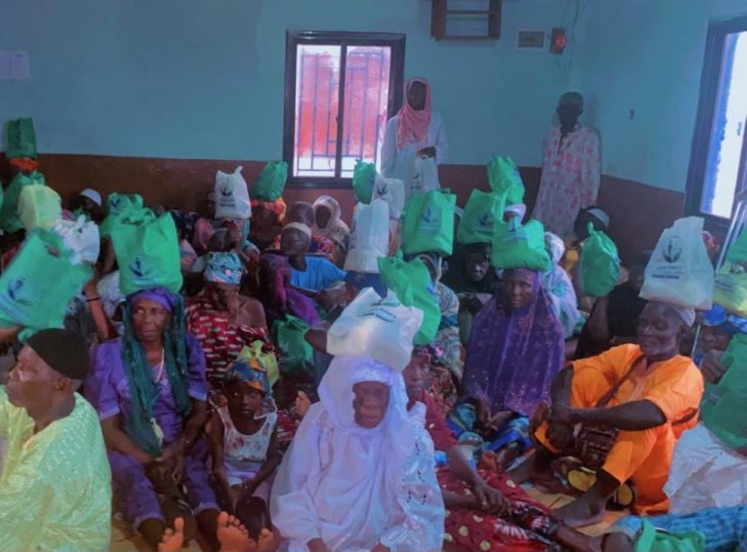 Older adults and community members gathered with food-support bags in Port Loko