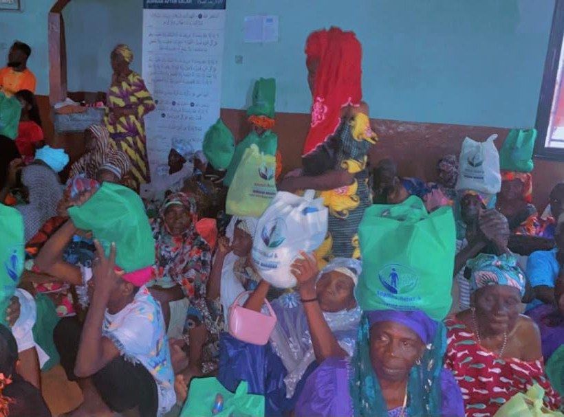 Community members holding green and white food-support bags during distribution