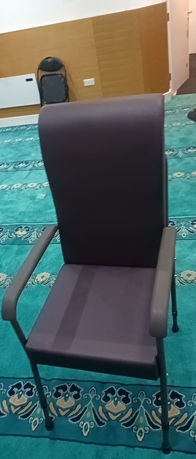 The supportive high-back chair with armrests provided for an older worshipper at the mosque