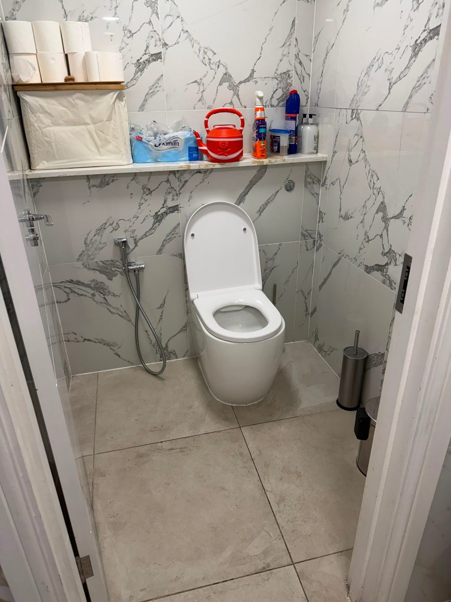 The mosque toilet cubicle before the project, with no support frame or rail beside the toilet